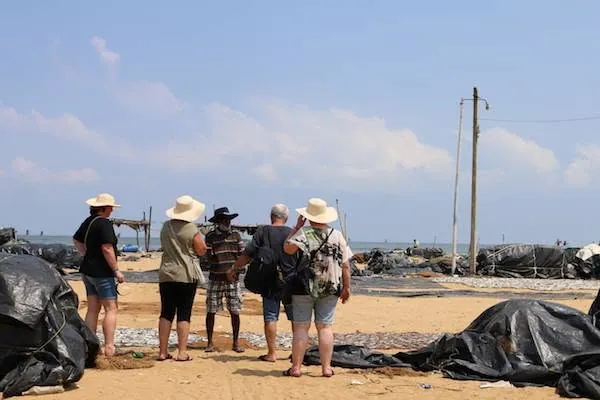 スリランカの浜辺で、現地のガイドと話す旅行者たち